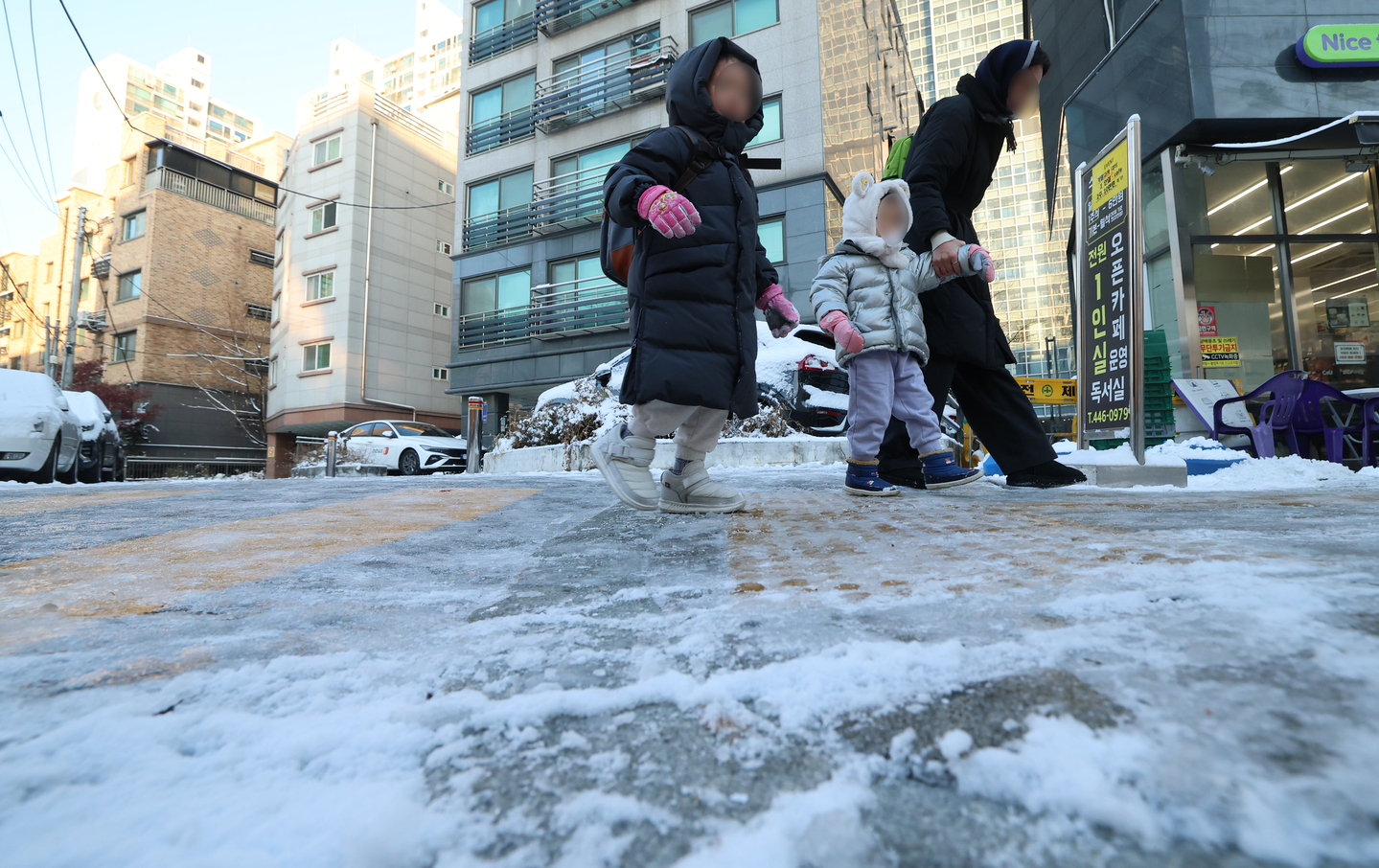 A woman walks with children on an icy road in Gwangjin District, eastern Seoul, on the morning of Dec. 5, as a cold wave froze roads across the capital following heavy snowfall the previous night. [NEWS1]