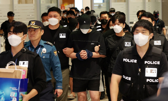 Police escort repatriated Koreans involved in Cambodia-based scam organizations as they move through Terminal 2 of Incheon International Airport on Oct. 18. [JOINT PRESS CORPS]