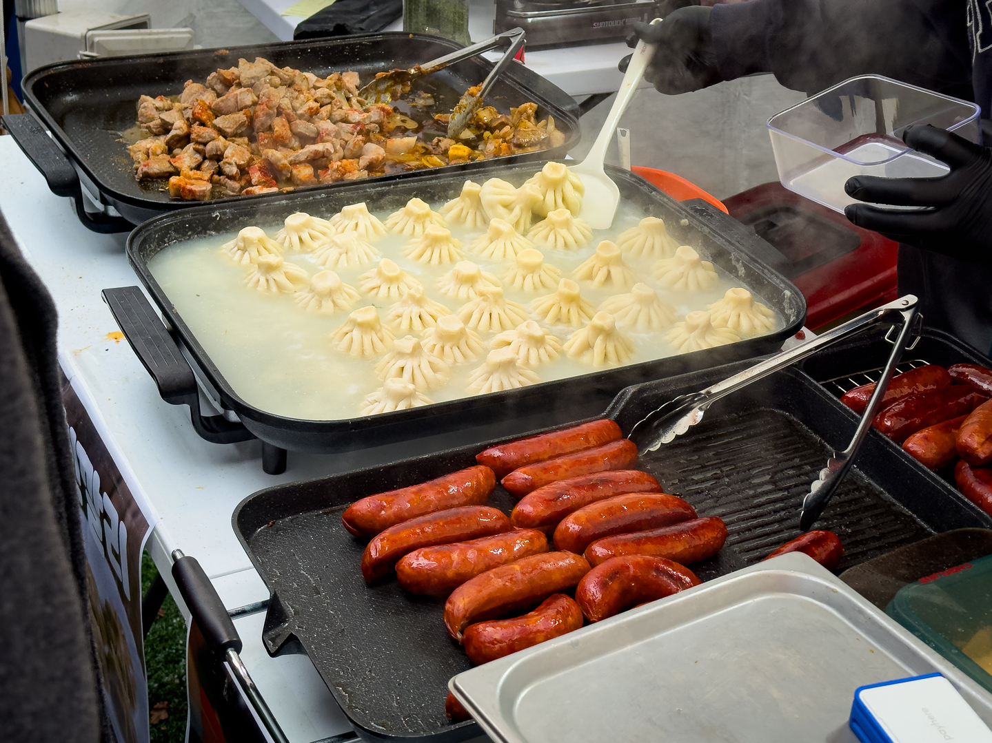 From left: Ojakhuri, a dish of cooked pork and potatoes, khinkali soup dumplings and kupati sausages are almost ready to be served to patrons at the Georgian booth of the European Market in Seongbuk District, central Seoul, on Dec. 6. [MICHAEL LEE]