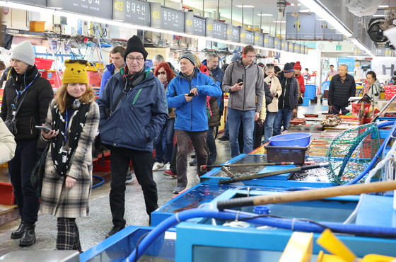 Foreign tourists look around Jagalchi Market in Busan on Dec. 4. [YONHAP]