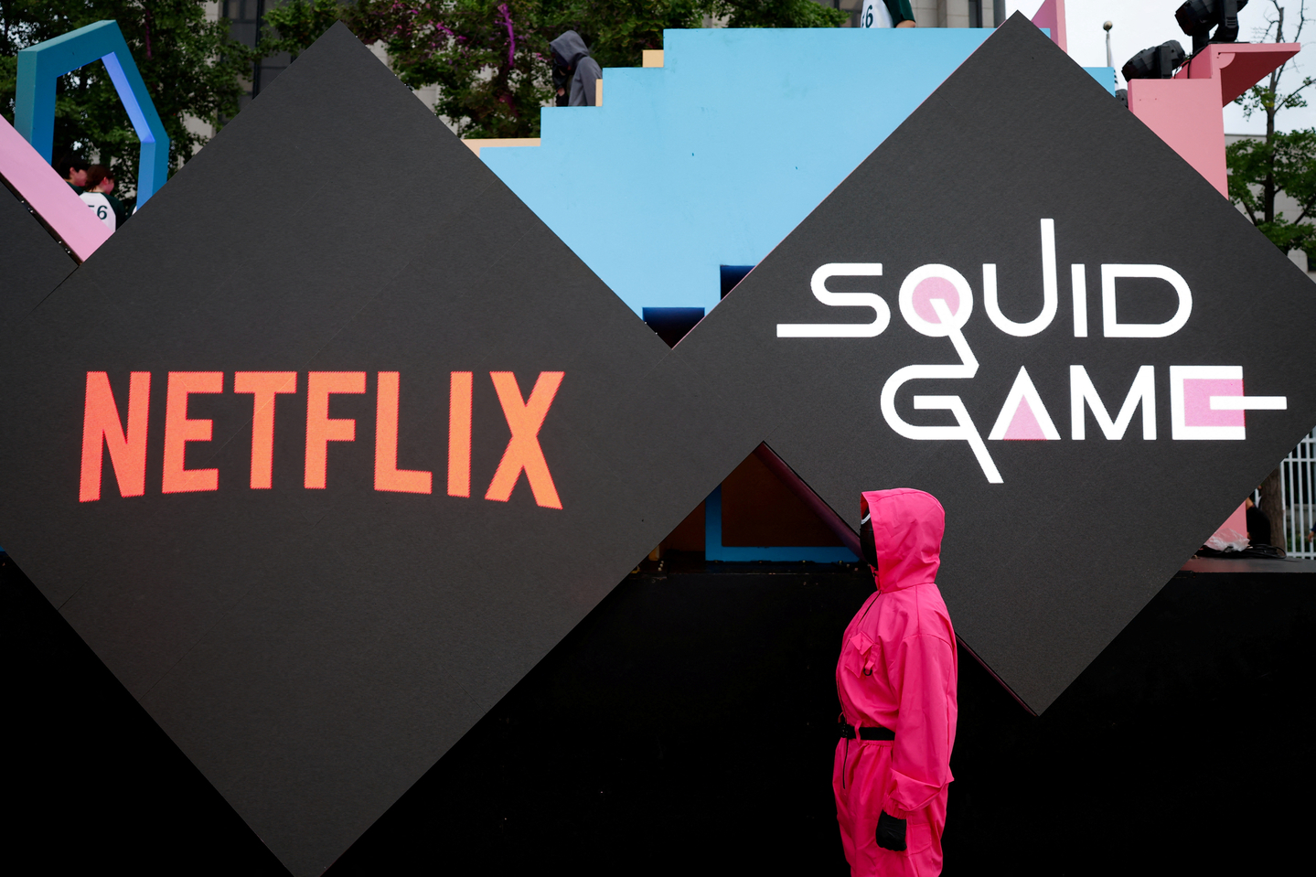 A performer dressed as a ″Squid Game″ soldier stands in front of the Netflix and ″Squid Game″ logos before a parade through central Seoul, followed by a fan event with the cast to celebrate the release of the third season of Netflix's hit series in Seoul on June 28. [REUTERS/YONHAP]