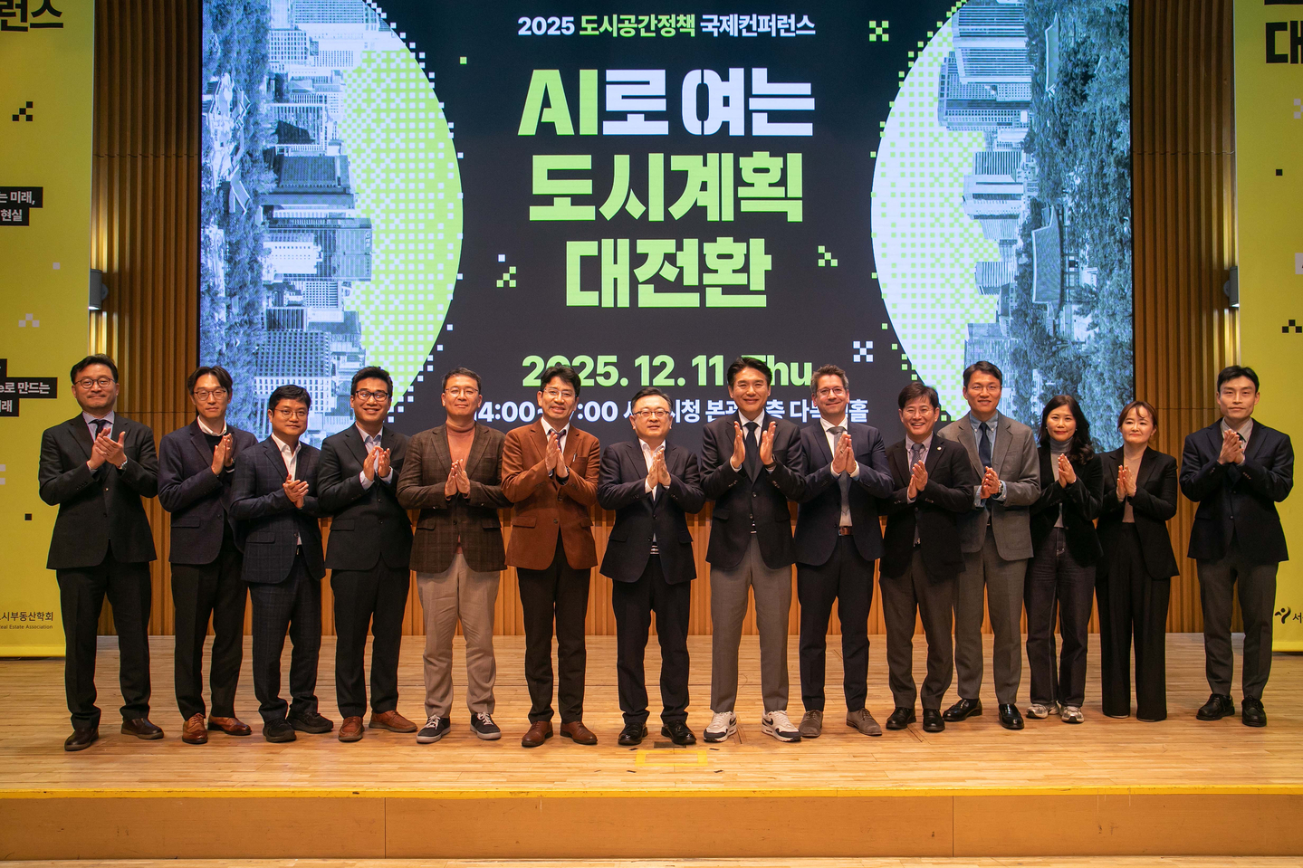 Speakers and participants clap during a group photo session at the “AI and the Great Transformation of Urban Planning” conference at City Hall in central Seoul on Dec. 11. [SEOUL METROPOLITAN GOVERNMENT] 