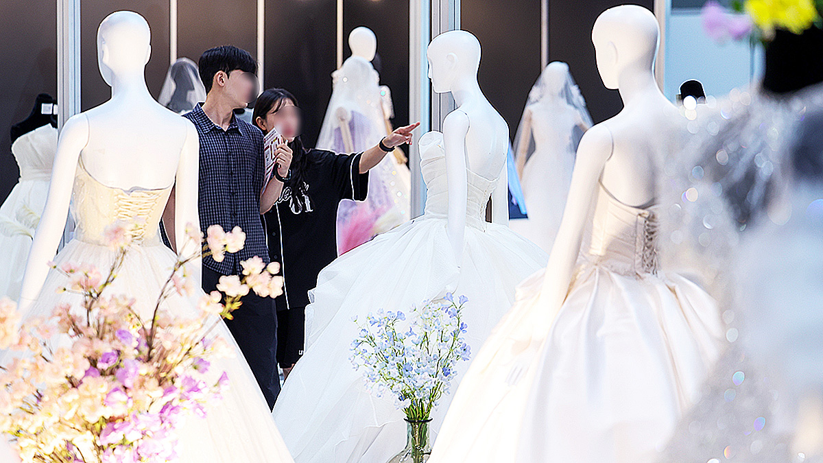 Couples browse wedding dresses at a wedding fair at Coex in Gangnam District, southern Seoul, on July 6. [NEWS1]
