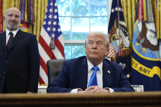 U.S. President Donald Trump, right, and U.S. Commerce Secretary Howard Lutnick listen to a reporter's question in the Oval Office of the White House in Washington on Sept. 19. [AP]
