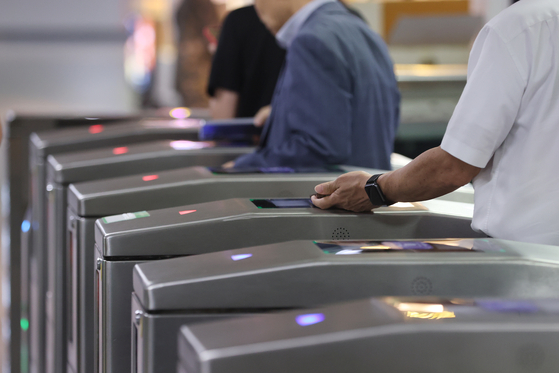 Passengers on a Seoul subway line are seen tagging their phones to pass the subway gate at a station in Seoul on July 22. [YONHAP]