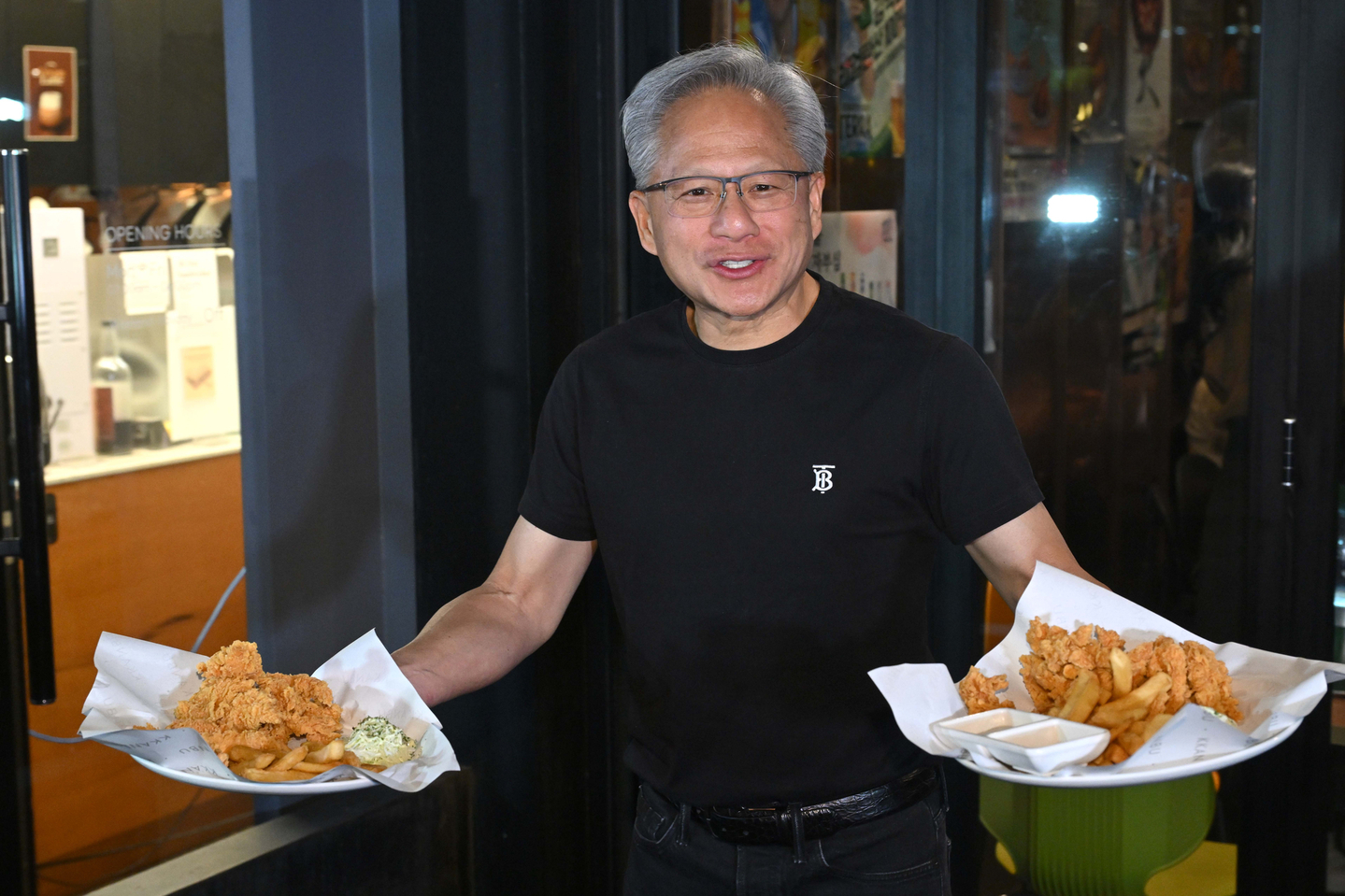Nvidia CEO Jensen Huang hands out chicken and French fries to customers during a dinner with Samsung Electronics Chairman Lee Jae-yong and Hyundai Motor Group Executive Chair Chung Euisun at a Kkanbu Chicken restaurant in Samseong-dong, southern Seoul, on Oct. 30. [YONHAP]