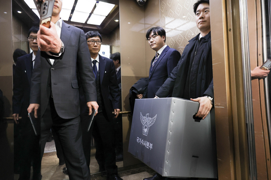 Police investigators carry a box with seized items after conducting a raid on the office of former Oceans Minister Chun Jae-soo at the National Assembly in Yeoudio, western Seoul, on Dec. 15. Chun stepped down last week over allegations of accepting bribes from the Unification Church. The search and seizure of Chun’s office took over two hours to get started, longer than the norm for such parliamentary raids. [LIM HYUN-DONG] 