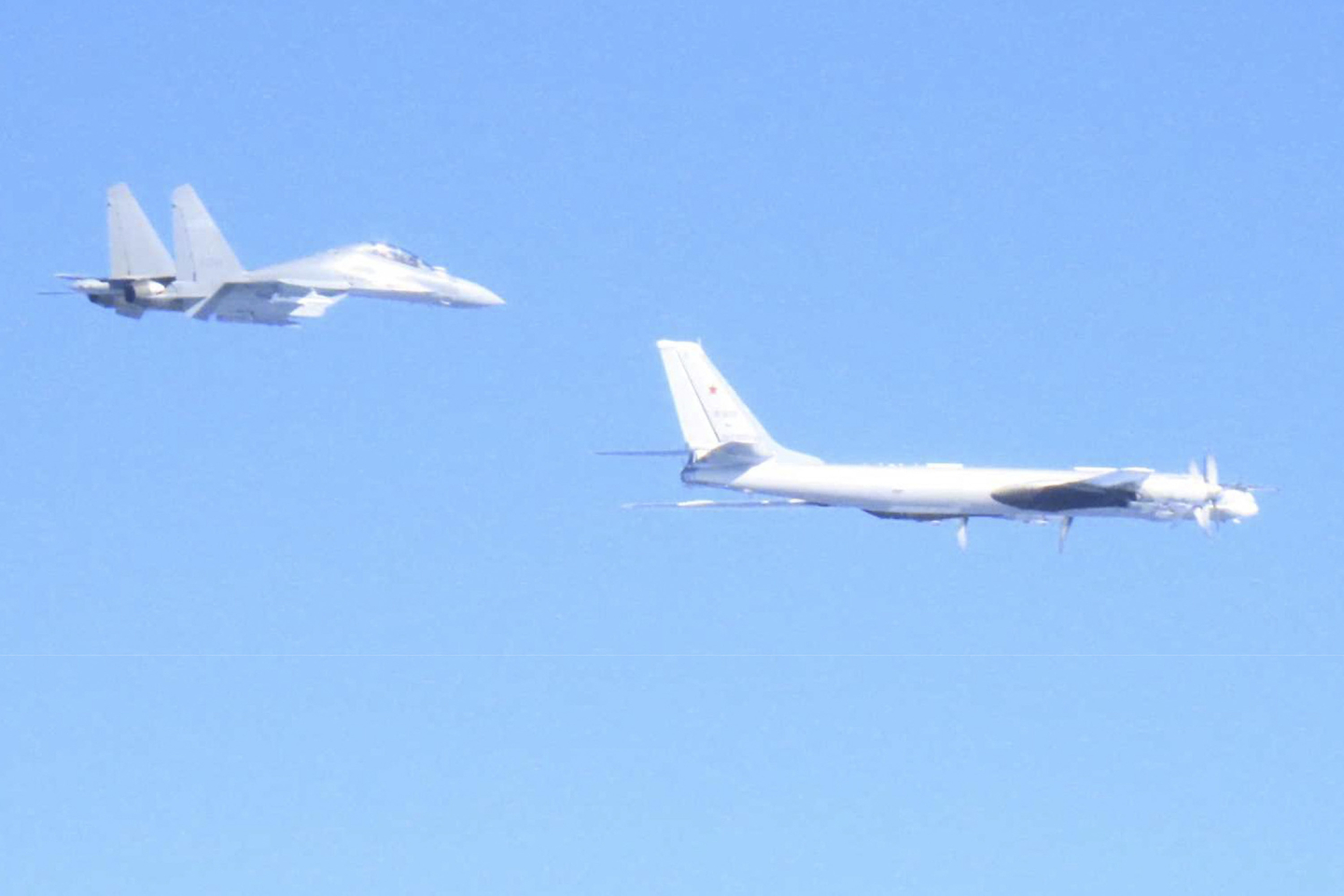 This handout photo taken on Dec. 9 and received on Dec. 10 from Japan's Ministry of Defense shows a Chinese J-16 fighter jet (L) and a Russian Tu-95 bomber during a joint flight over the sea near Japan. South Korea and Japan reacted furiously on Dec. 10 after Chinese and Russian military aircraft conducted joint patrols around the two countries, with both Seoul and Tokyo scrambling jets. [AFP/YONHAP, JAPAN'S MINISTRY OF DEFENSE HANDOUT]