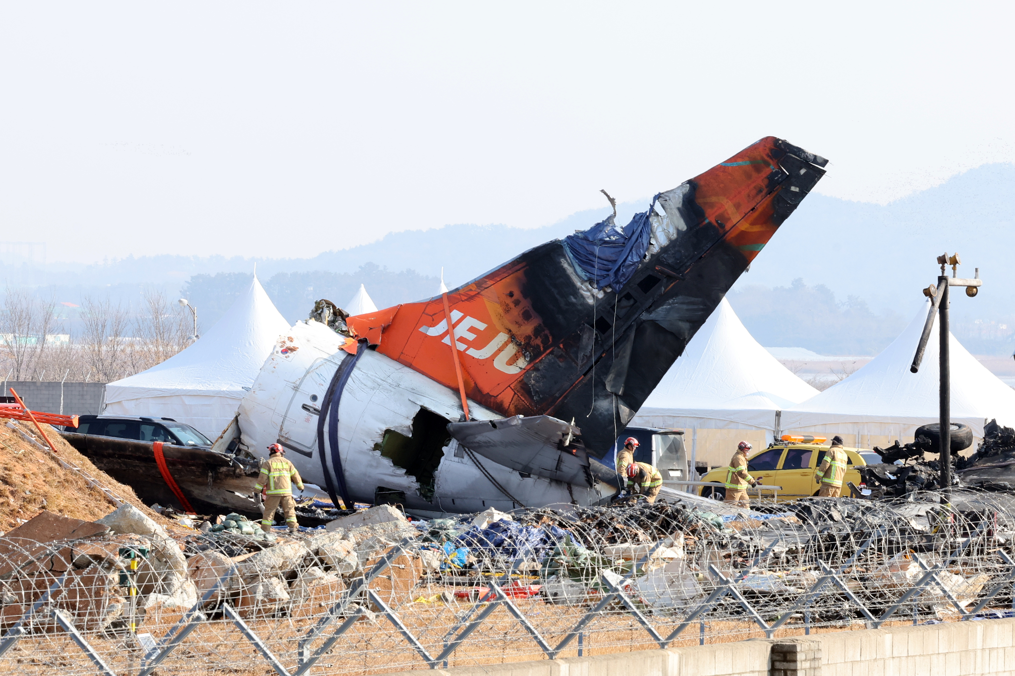 Firefighters remove tarps covering the debris of a Jeju Air passenger plane at Muan International Airport in South Jeolla on Jan. 13 following its crash on Dec. 29, 2024. [YONHAP]