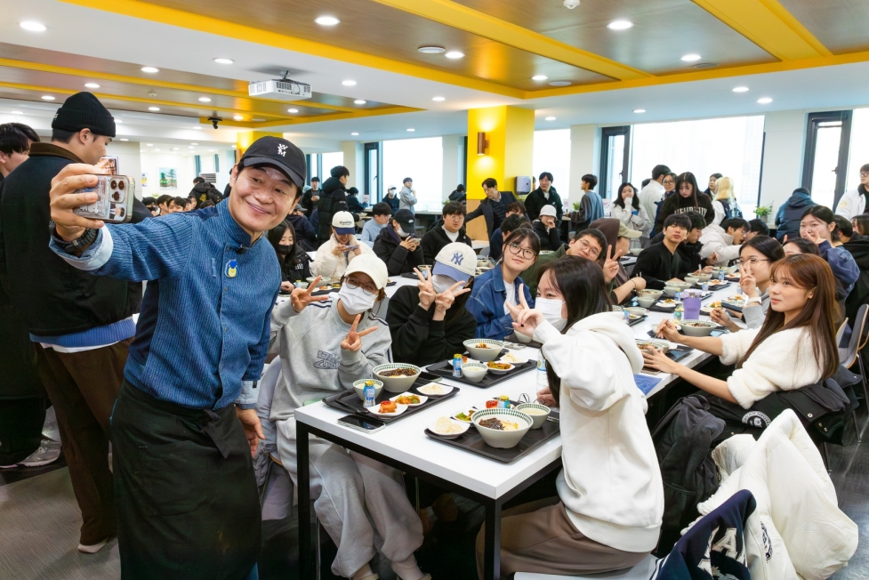 Chef Lee Yeon-bok, left, poses for a photo with students at Hanyang University on Dec. 15. Chef Lee visited the university in Seongdong District, eastern Seoul, to take part in the school’s regular “1,000 won breakfast” campaign. [HANYANG UNIVERSITY]