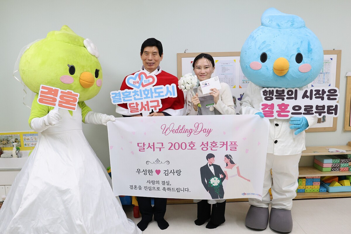 Daegu Dalseo District Mayor Lee Tae-hoon, left, and Kim Sa-rang, a Dalseo resident who met her husband through the Dalseo Marriage Promotion Team's program to become the 200th couple matched by the district office, pose for a commemorative photo [DALSEO DISTRICT OFFICE]