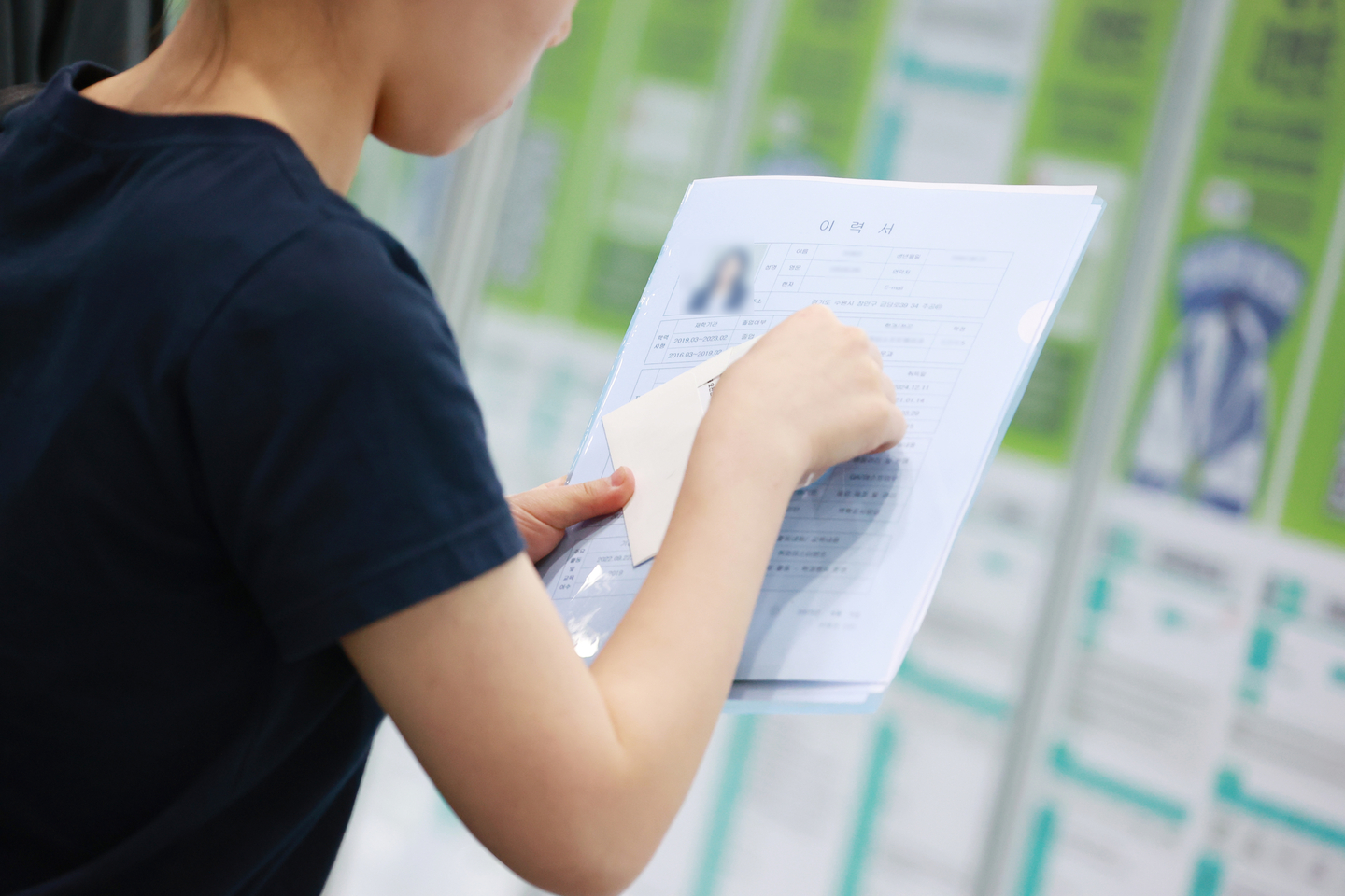 A job seeker holds up a resume, which includes a photo on the top left, at the 2025 Gangnam Job Fair at Coex in Gangnam District, southern Seoul, on June 5. [YONHAP] 