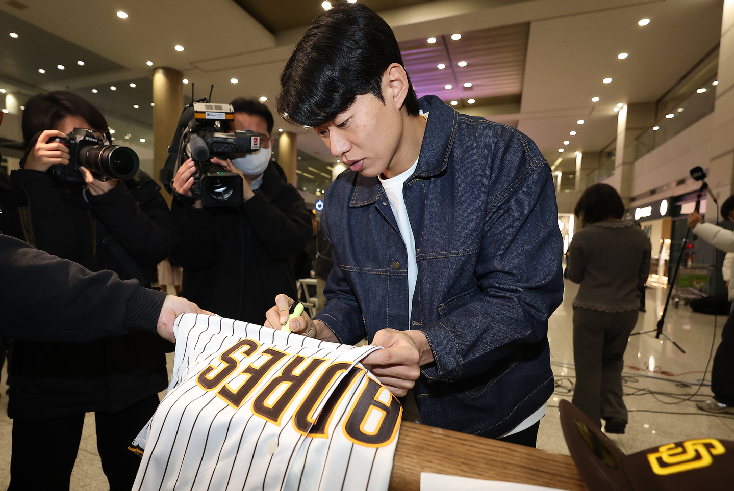 Song Sung-mun of the San Diego Padres signs a Padres jersey for a fan at Incheon International Airport, west of Seoul, on Dec. 23. [YONHAP]