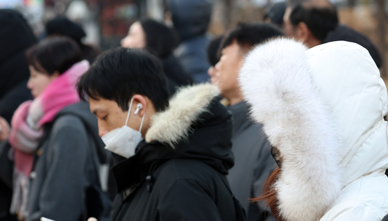 People clad in thick coats, mufflers and gloves walk on a street near Gwanghwamun Square in Jongno District, central Seoul on Dec. 12. [NEWS1]