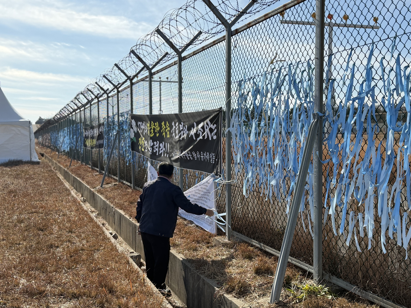 Park In-wook, 69, picks up litter around the fence area close to the runway of Muan International Airport in South Jeolla, where an airplane carrying his families crashed last year, on Dec. 22. [LEE SOO-JUNG]