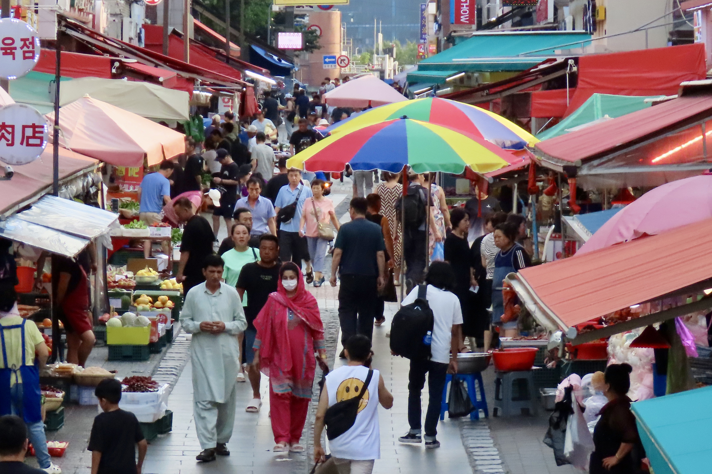 People walk down the multicultural food street market in Danwon District, Ansan, Gyeonggi, on July 29. Foreign workers heading home after daytime shifts mix with those heading to night work, alongside foreign merchants and residents. As of 2023, Ansan has the largest foreign population in Korea, at about 108,000. [KIM HONG-JUN]