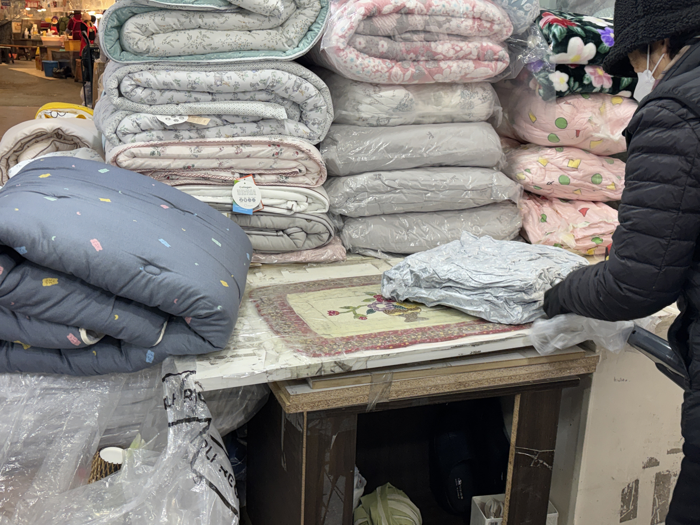 A merchant vacuum-seals a blanket for a customer at Gwangjang Market in Jongno District, central Seoul, on Dec. 22. [KWAK JOO-YOUNG]