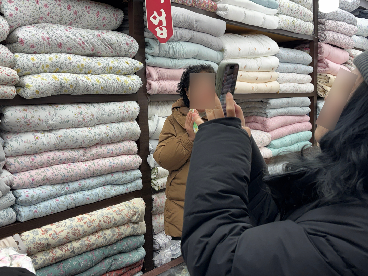 A shopper video calls an acquaintance while buying blankets at Gwangjang Market in Jongno District, central Seoul, on Dec. 22. [KWAK JOO-YOUNG]