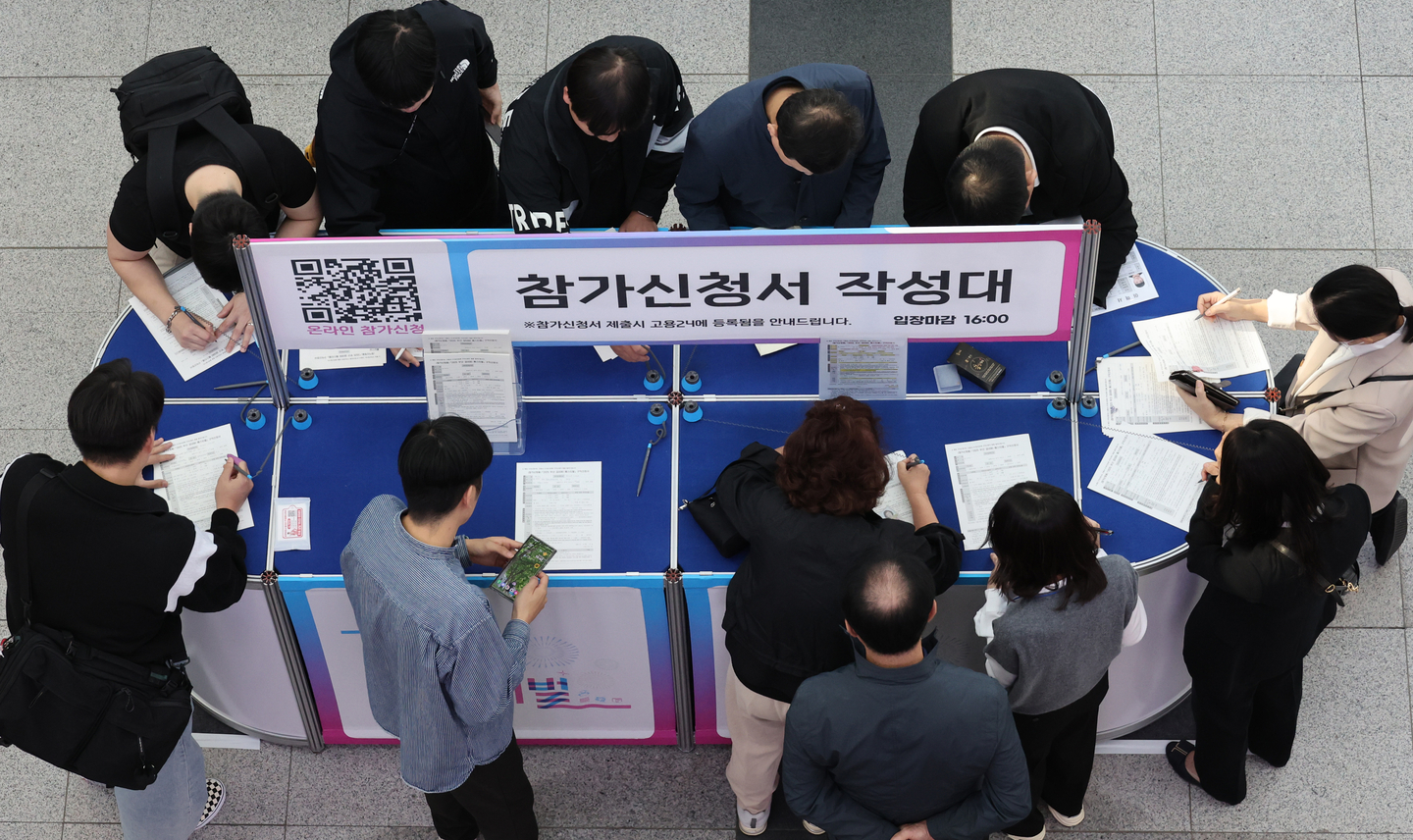 Job seekers are seen filling out application forms at a job fair held at Bexco in Busan on Oct. 27. [SONG BONG-GEUN]