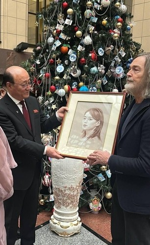 Two men hold up a portrait of Kim Yo-jong, the sister of North Korea leader Kim Jong-un, which Maria Zakharova, the spokesperson for Russia's foreign ministry, prepared to send to Kim Yo-jong as a gift, in this photo from Zakharova's Telegram account. [SCREEN CAPTURE]