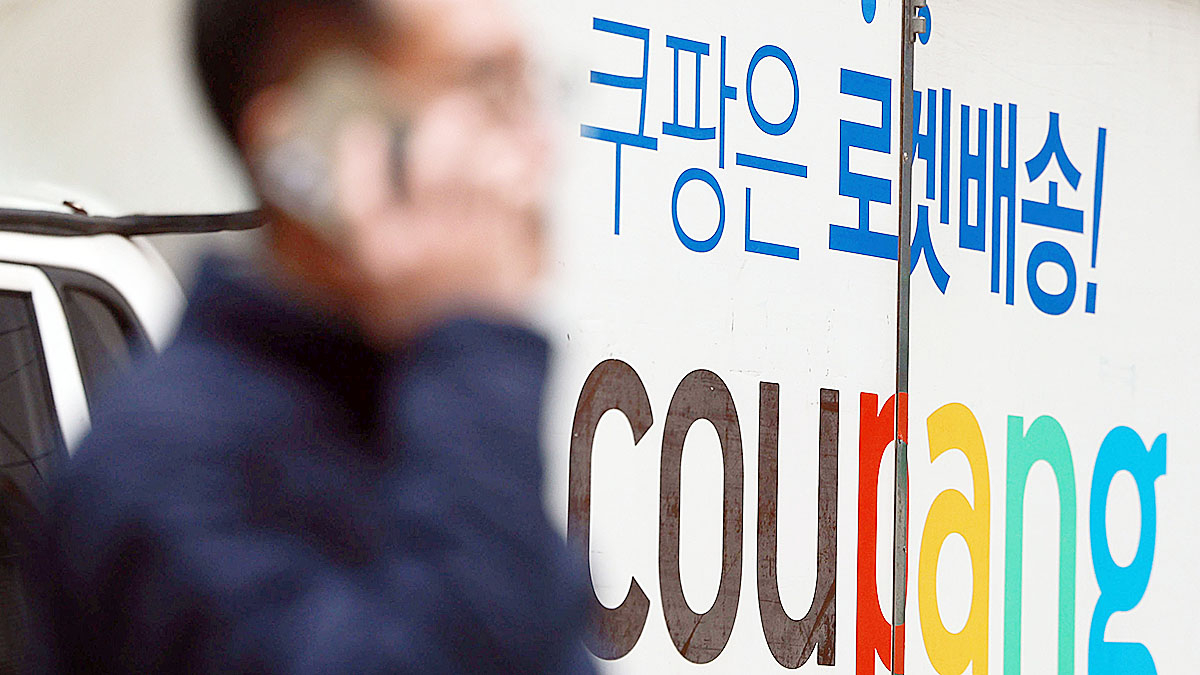 A person walks by a Coupang delivery truck in Seoul on Dec. 28. [YONHAP] 