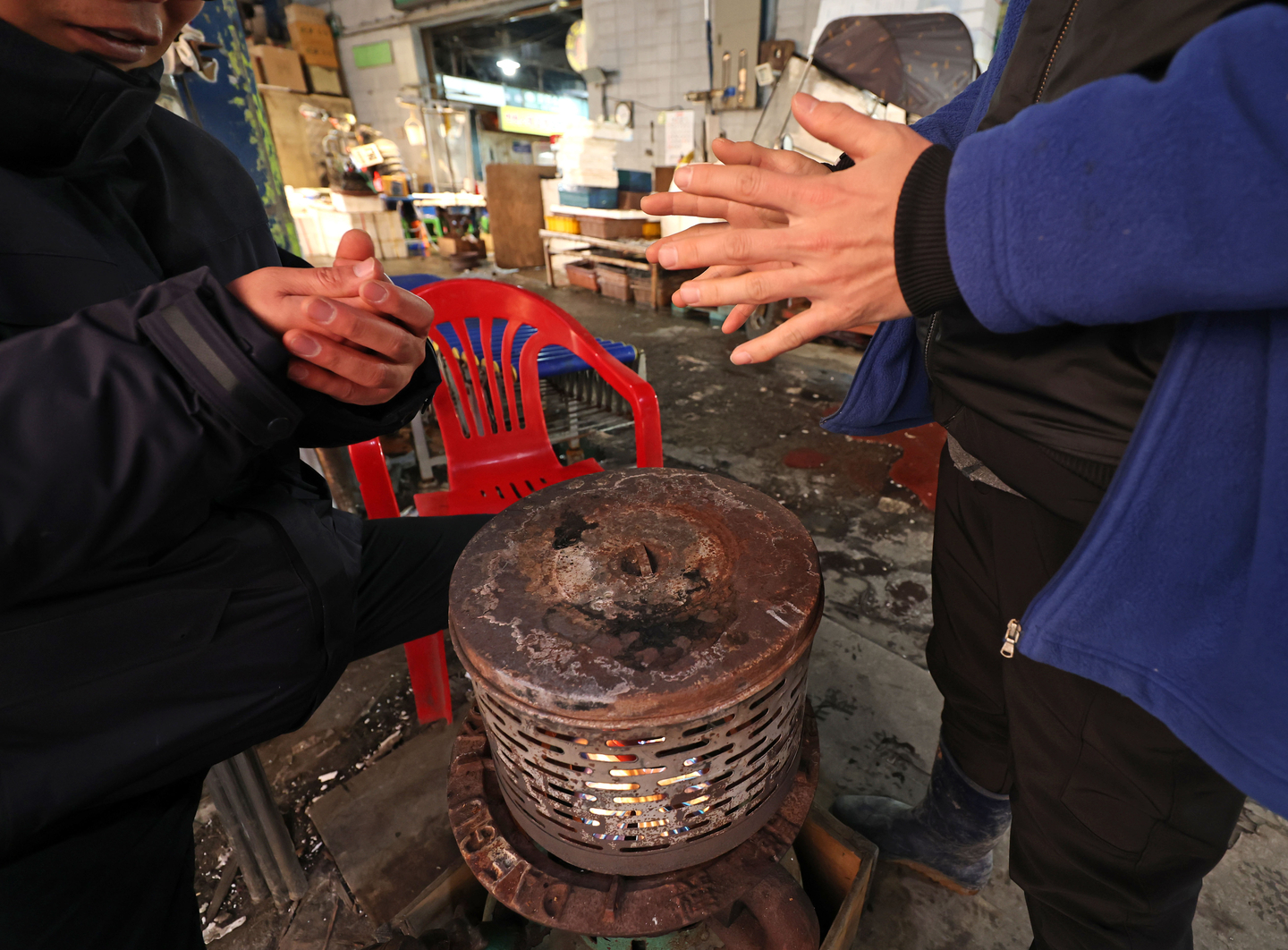Merchants warm their hands in front of a heater at the Garak Market in Songpa District, southern Seoul, on Dec. 26. [YONHAP]