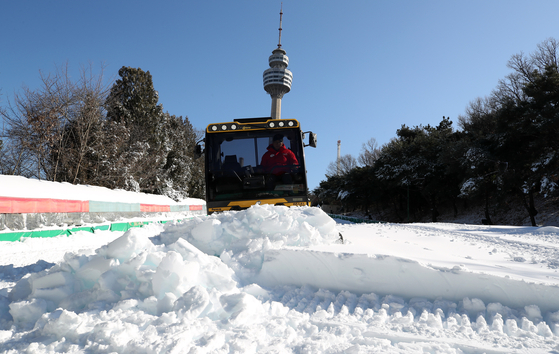 Employees level piled artificial snow to create a sledding slope at the E-World theme park in Dalseo District, Daegu, on Jan. 2, as a cold wave continues. [NEWS1] 