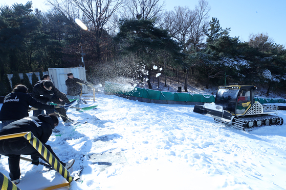 Employees level piled artificial snow to create a sledding slope at the E-World theme park in Dalseo District, Daegu, on Jan. 2, as a cold wave continues. [NEWS1] 