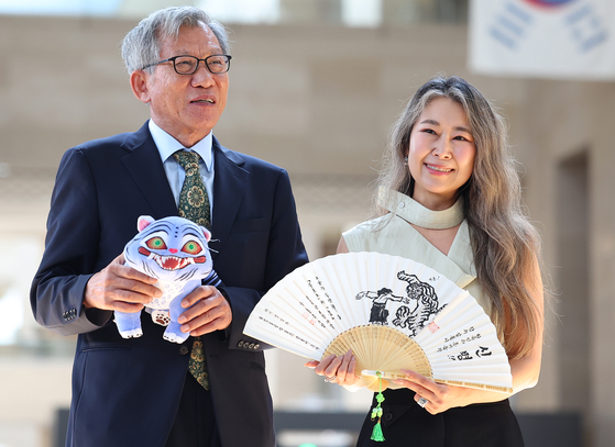 National Museum of Korea Director Yoo Hong-jun, left, and "KPop Demon Hunters" director Maggie Kang hold presents given to each other at the museum in central Seoul on Thursday. Yoo holds a stuffed tiger named "Derpy" from the film, and Kang holds fan drawn with tiger xylograph. The National Museum of Korea saw surge of international visitors thanks to its museum merchandises that resemble animals appearing in "KPop Demon Hunters." [YONHAP]