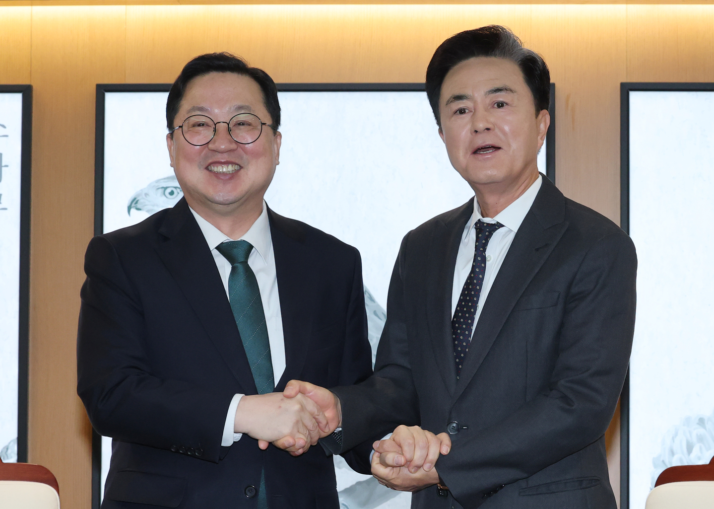 South Chungcheong Gov. Kim Tae-heum, right, and Daejeon Mayor Lee Jang-woo shake hands ahead of a meeting on the proposed administrative merger of Daejeon and South Chungcheong at the South Chungcheong Provincial Government Office on the morning of Dec. 24, 2025. [NEWS1]