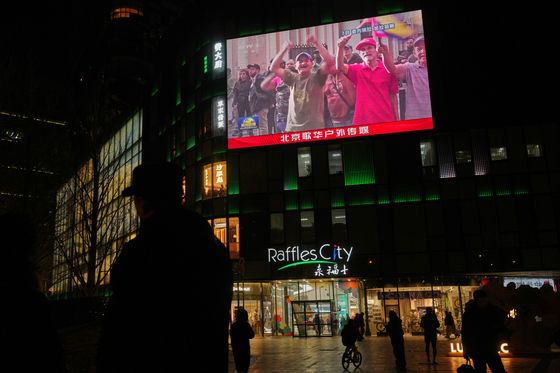 People gather near a large screen at a shopping mall showing CCTV broadcasting people in a rally in Caracas, Venezuela, after U.S. President Donald Trump announced that U.S. forces had captured Venezuelan President Nicolas Maduro and his wife, in Beijing on Jan. 4. [AP/YONHAP]