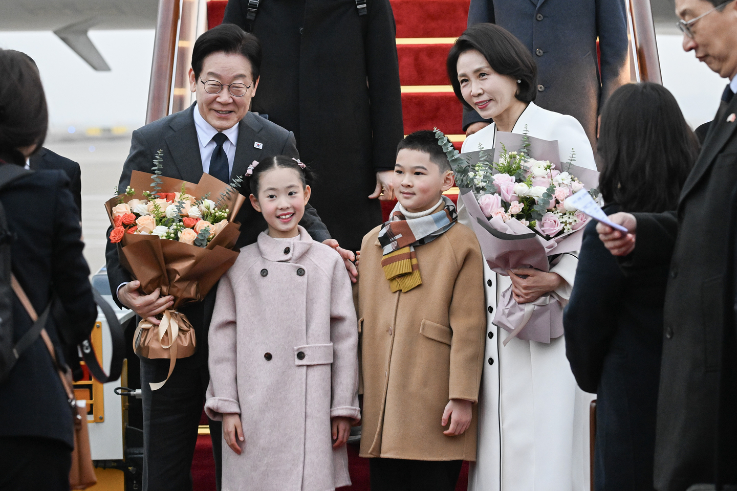 President Lee Jae Myung, left, and first lady Kim Hea Kyung, right, pose for a photo with children presenting flowers upon their arrival at Shanghai Pudong International Airport on Jan. 6, the final stop of Lee’s two-city, four-day state visit to China. [JOINT PRESS CORPS]
