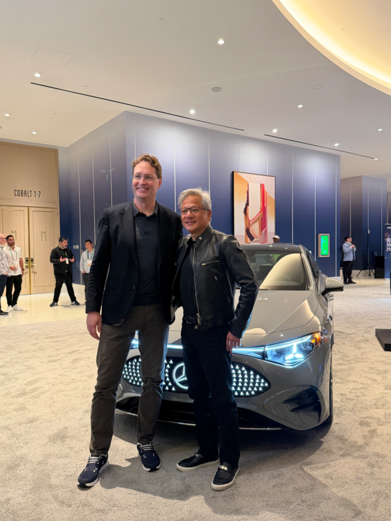 Nvidia CEO Jensen Huang, right, and Mercedes-Benz Chairman Ola Kallenius pose for a photo with the Mercedes CLA after the two hold a private meeting at the CES 2026 in Las Vegas on Jan. 6. [SARAH CHEA]