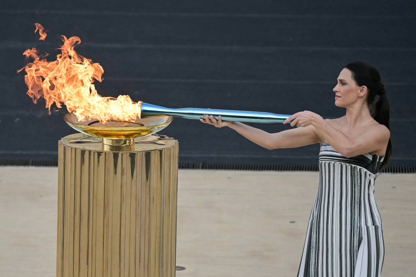 Greek actress Mary Mina, playing the role of the High Priestess, lights the Olympic torch during the handover Olympic flame ceremony for the Milano-Cortina 2026 Winter Olympic Games and Paralympic Games at the Panathinean stadium in Athens, Greece on Dec. 4, 2025. [AFP/YONHAP] 