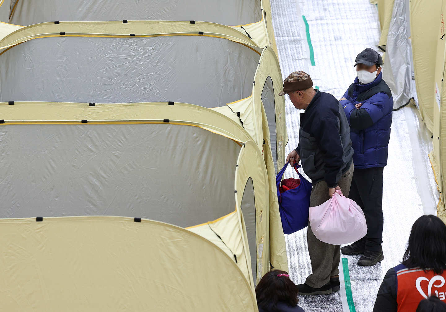 At a wildfire evacuation shelter set up at the Uiseong Gymnasium in North Gyeongsang, a resident moves personal belongings into an emergency relief shelter to spend the night after a wildfire broke out in the county on Jan. 10. [YONHAP] 