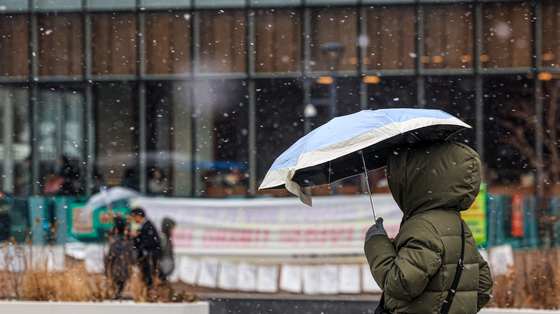People move through Gwanghwamun Square in central Seoul as snow falls on Jan. 12. [NEWS1]