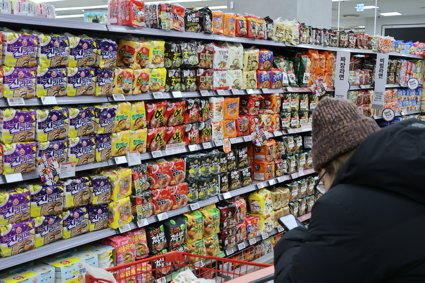 A shopper looks at instant noodles stocked at a supermarket in Seoul on Jan. 12. [YONHAP]