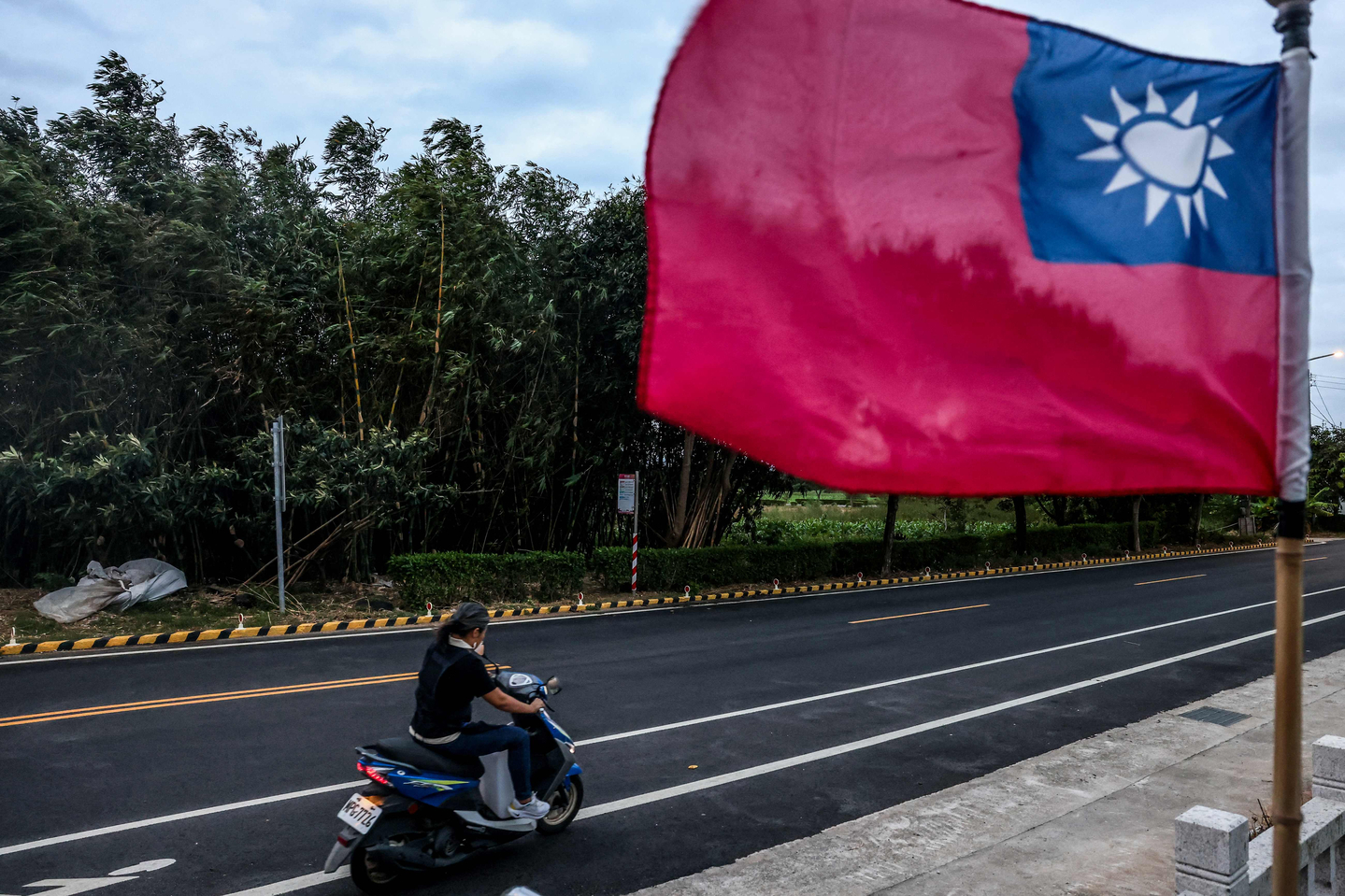 A person rides a scooter passing by a Taiwanese flag in Kinmen on Oct. 28, 2025. [AFP/YONHAP]