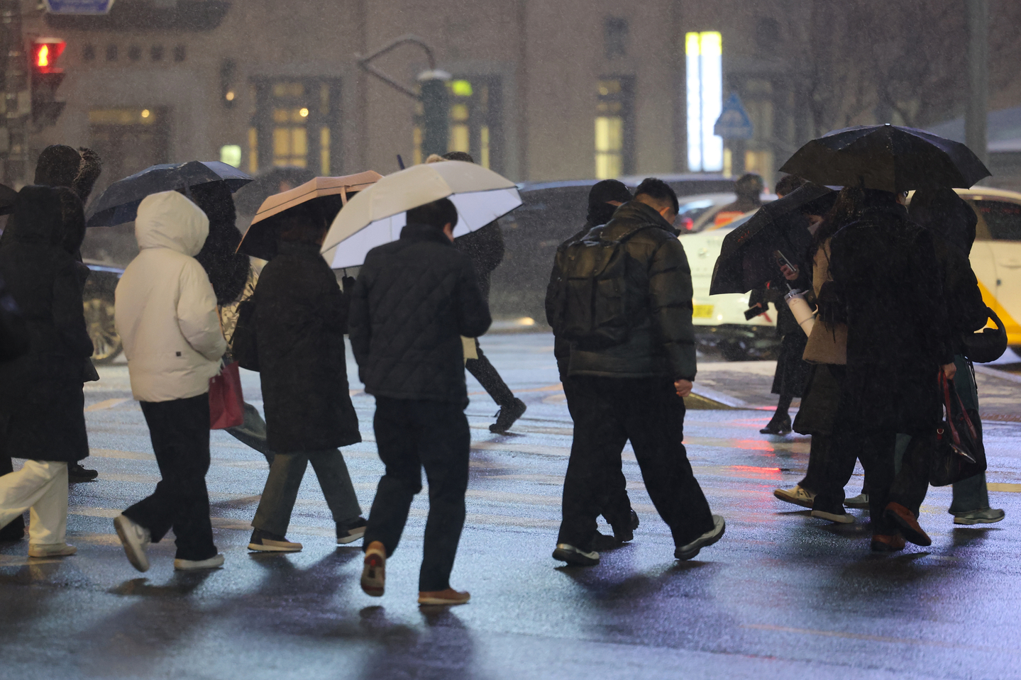 People walk through Gwanghwamun Square in Jongno District, central Seoul, using hoods and umbrellas as it snows on Jan. 12. [YONHAP]