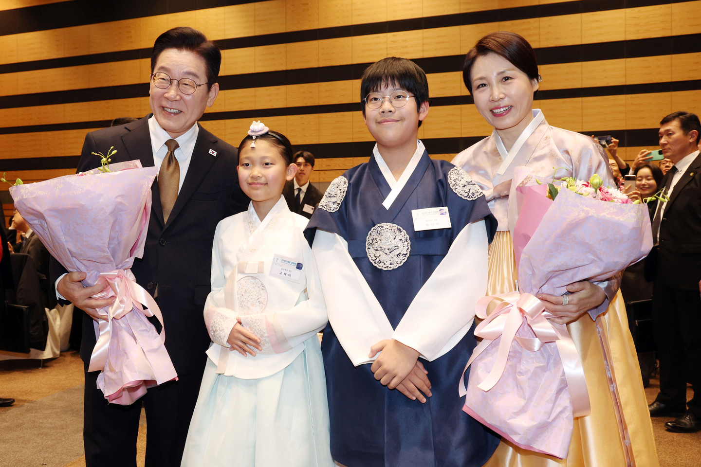 President Lee Jae Myung, far left, alongside his wife, Kim Hea Kyung, far right, poses for a photo with children after receiving flowers from them as he attends a meeting with Korean residents living in Nara on Jan. 14. [NEWS1]