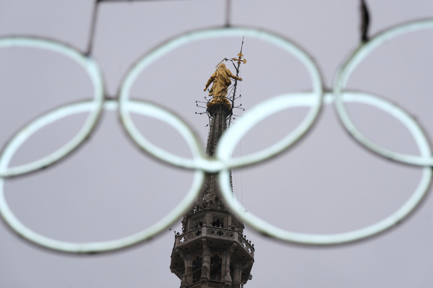 The statue of the Virgin Mary on the top of the Duomo Gothic cathedral is seen through Olympic Iconic neon rings ahead of the upcoming Milan Cortina Winter Olympics in Milan, Italy, on Jan. 9. [AP/YONHAP]