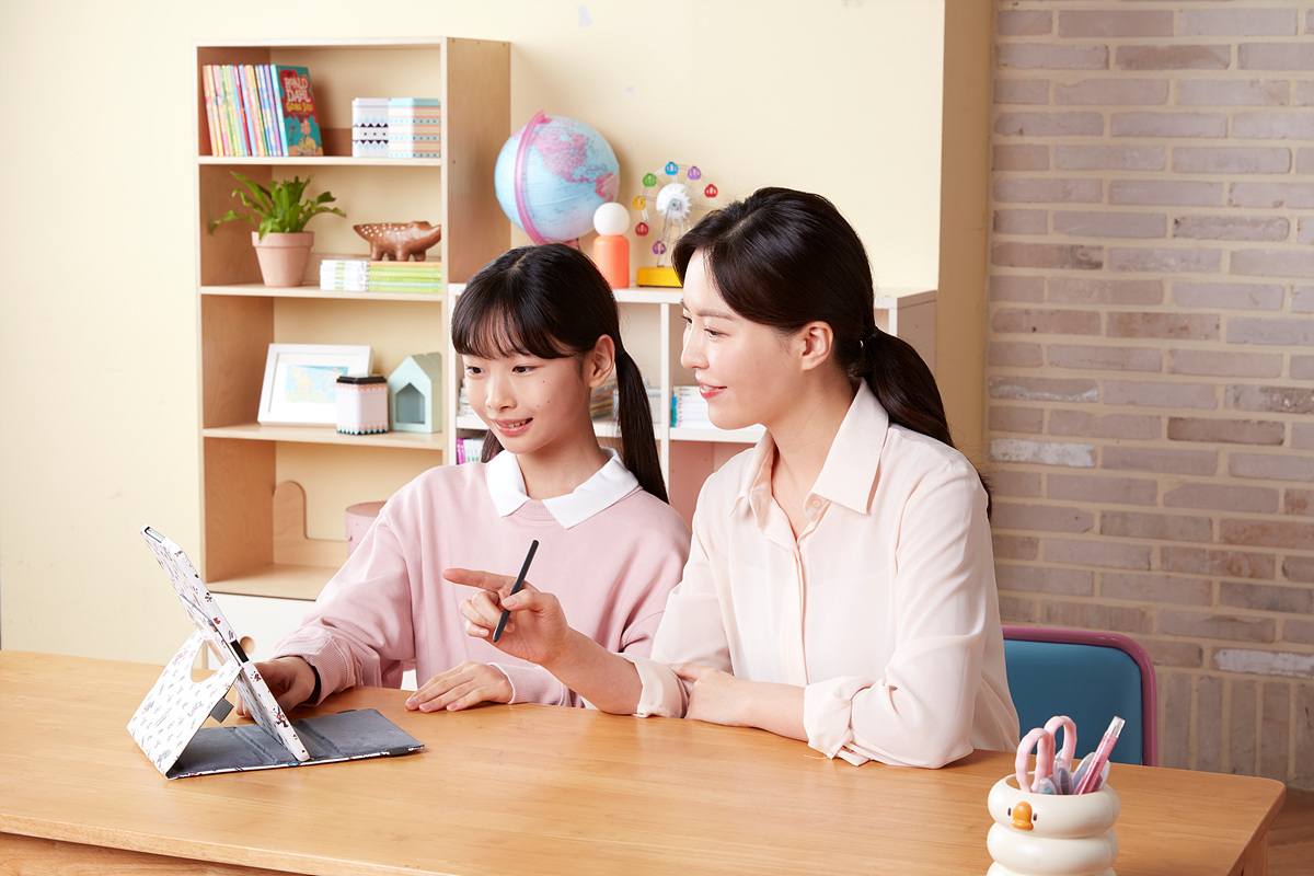 A Kumon teacher assists a student with her worksheet. [KYOWON]