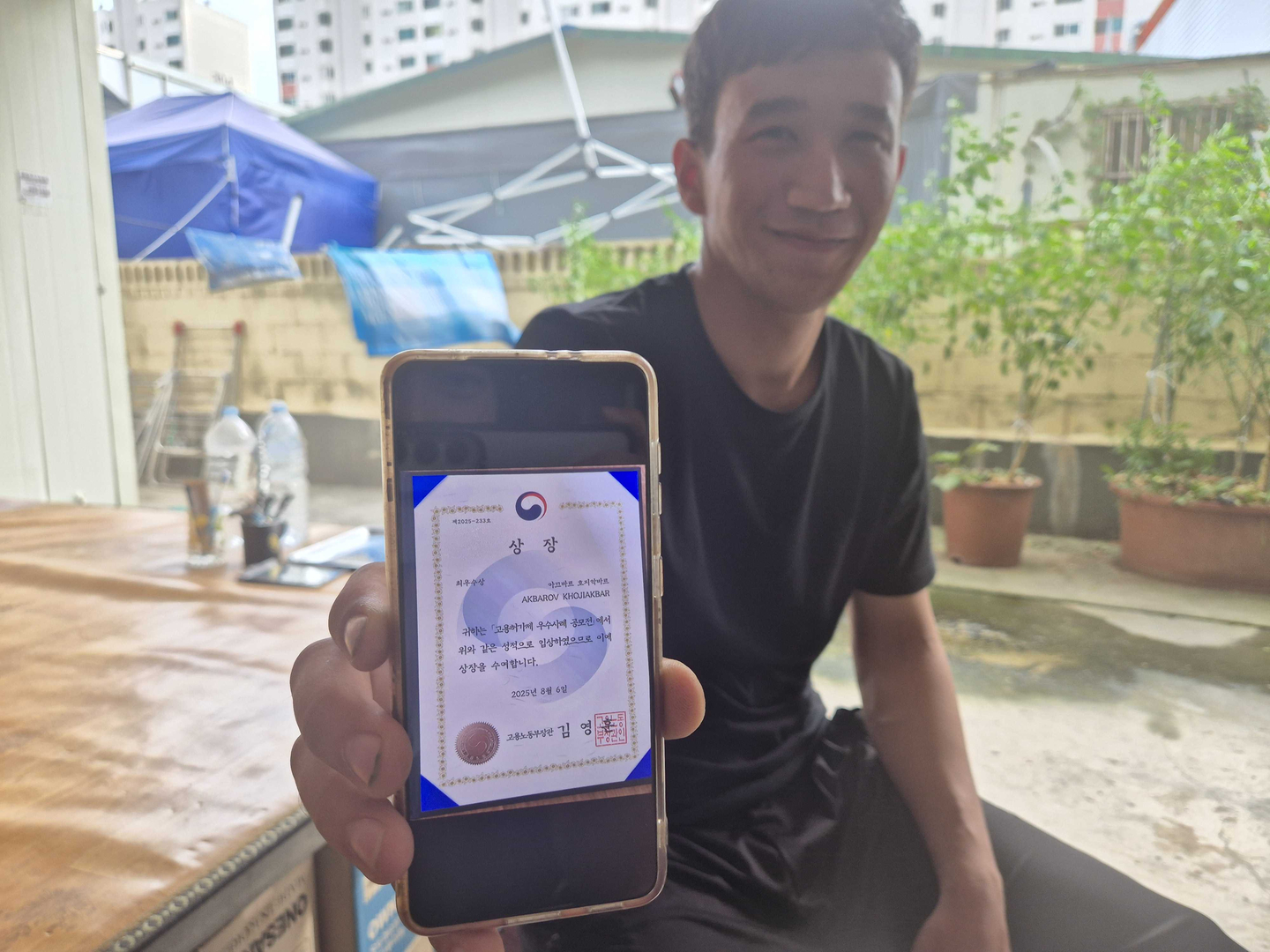 Khojiakbar Akbarov, an Uzbekistan national who entered Korea under the E-9 visa, shows a photo of his certificate for winning best foreign worker in Korea. [JUN YUL]