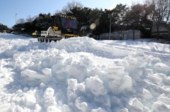 Employees level off piled artificial snow to create a sledding slope at the E-World theme park in Dalseo District, Daegu, on Jan. 2 as a cold wave continues. [NEWS1] 
