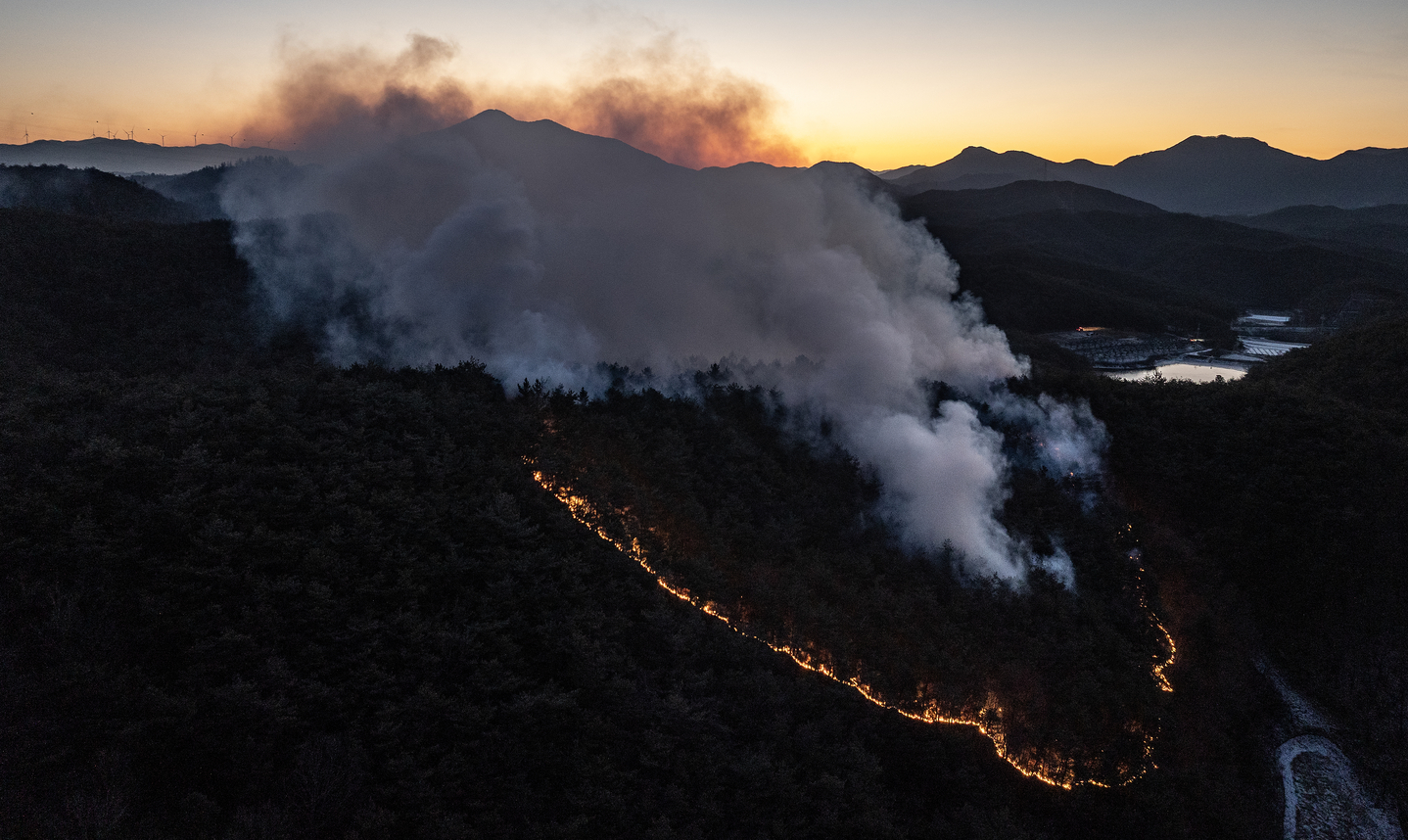 Embers from a wildfire that started the previous day continue to burn on a wooded hillside in Uiseong-eup, North Gyeongsang, on Jan. 11. [YONHAP] 