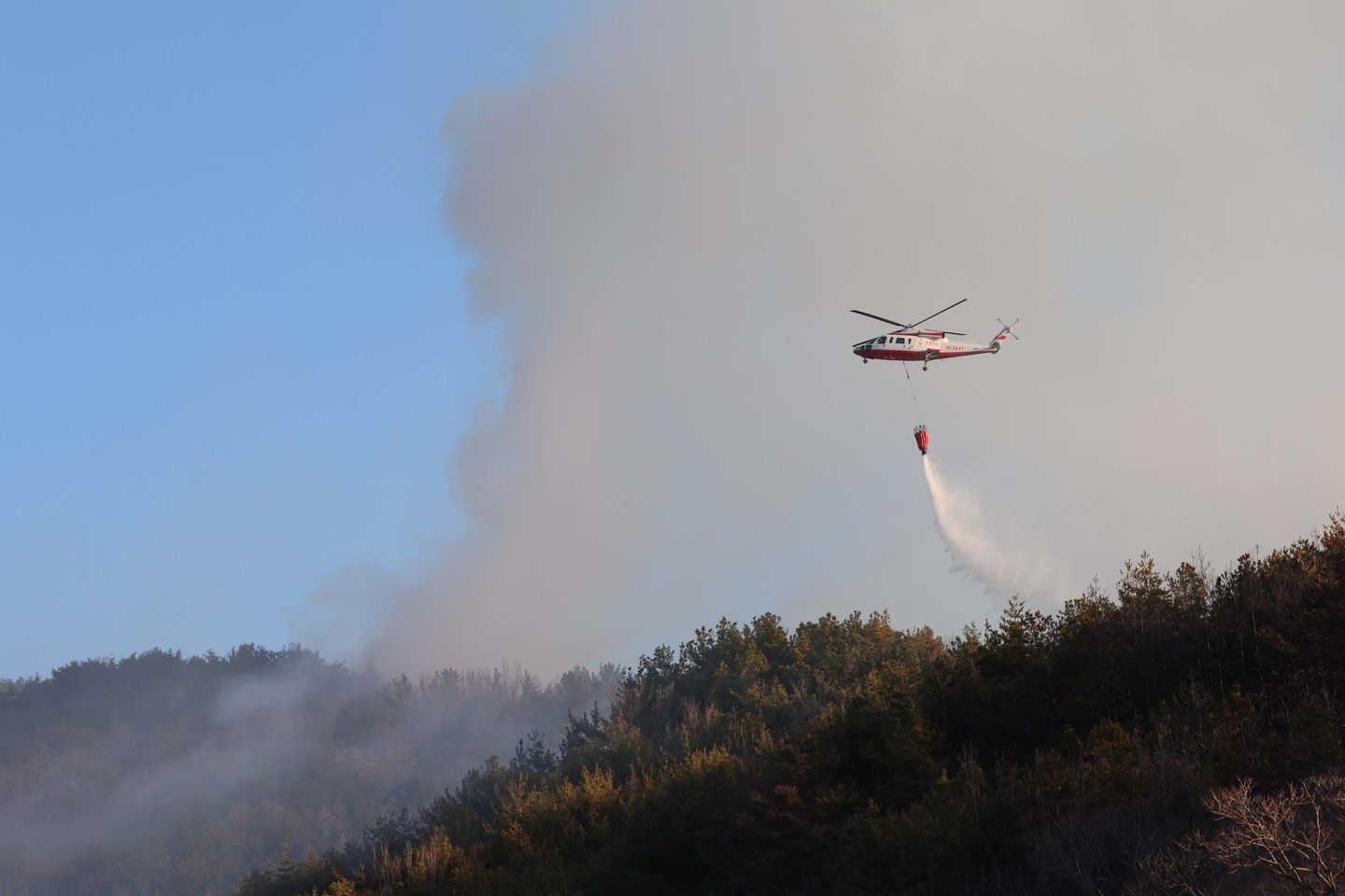 Helicopters are deployed to contain a wildfire in Gwangyang, South Jeolla, on Jan. 22, 2026. [YONHAP]