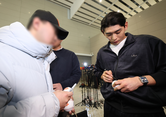 Lee Jung-hoo of the San Francisco Giants, right, signs a baseball for a fan at Incheon International Airport before departing for Los Angeles on Jan. 21, 2026. [YONHAP]