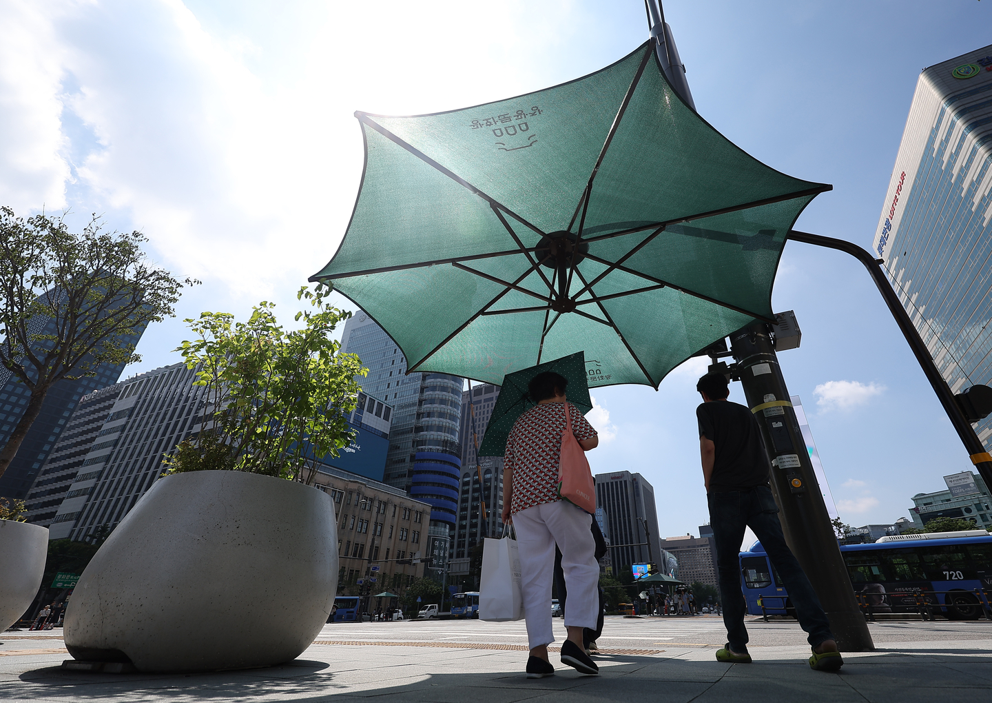 People seek shade to avoid the sun at Gwanghwamun Square in Jongno District, Seoul, on Aug. 5, 2025, amid a heat wave. [YONHAP]