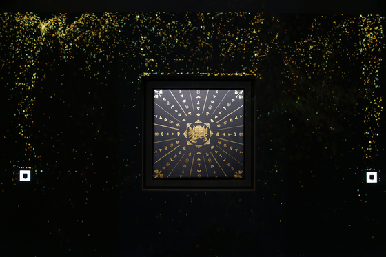 The geumbakjang, or gold-leaf imprinted work, “The Gleam of Ambition ‘Abundance,’” by Kim Gi-ho, which uses a projector to fill the space with layers of shimmering gold particles, at the CookieRun Kingdom’s “Legacy of the Kingdom” art exhibition at the Ara Art Center in Insa-dong in Jongno District, central Seoul. [CHO YONG-JUN]