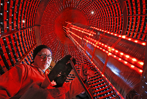Architect-artist Han Won-suk works on connecting the speakers and amplifiers inside a gigantic Emille Bell-inspired artwork made from 3,088 discarded speakers at his studio in Busan. [PARK SANG-MOON]